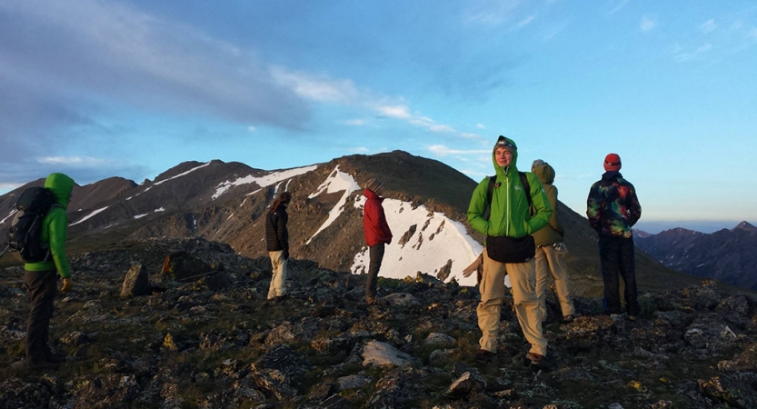 a group of people stand atop a rocky landscape looking in different directions 